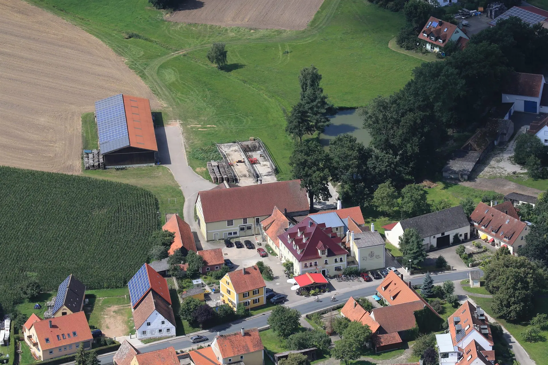 Luftaufnahme des Gasthaus Gößwein mit Hof, Teich und umliegenden Feldern in Mörsach