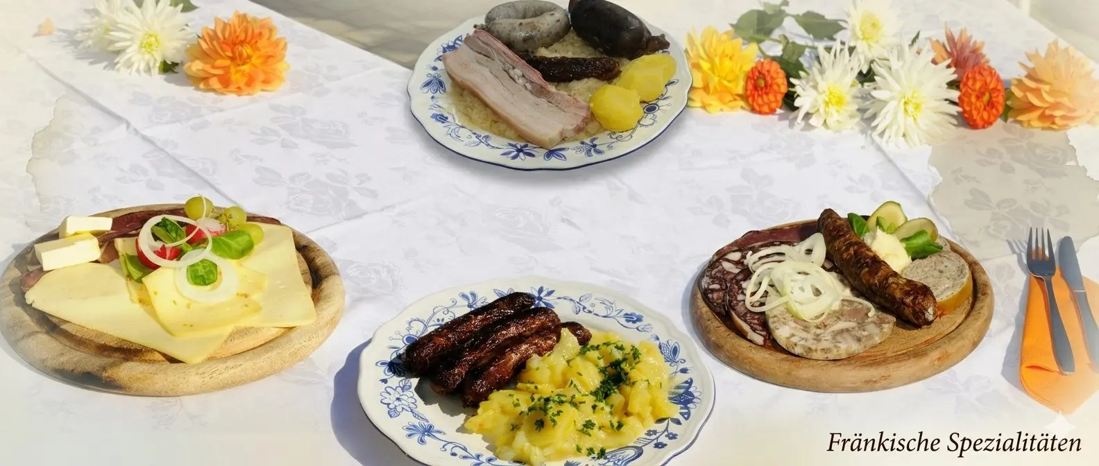 Tisch mit fränkischen Spezialitäten: Schlachtschüssel, Bratwürste mit Kartoffelsalat, Käse- und Brotzeitplatte