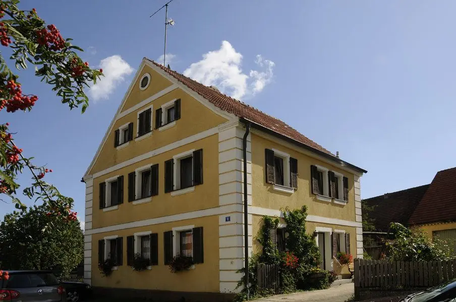Gelbes fränkisches Gästehaus des Gasthaus Gößwein mit Fensterläden und Blumenschmuck