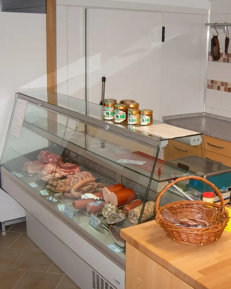 Hofladen-Theke mit Fleisch, Wurst und hängenden Würsten aus eigener Herstellung