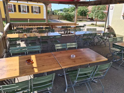 Überdachter Biergarten des Gasthaus Gößwein mit Tischen und Stühlen