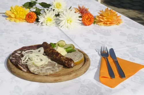 Fränkischer Brotzeitteller auf Holzbrett mit Blutwurst, Bratwurst, Sülze und Zwiebeln