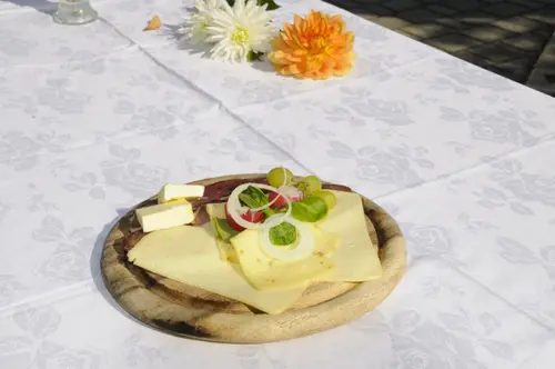 Fränkischer Käseteller mit Trauben, Radieschen und Zwiebeln auf Holzbrett