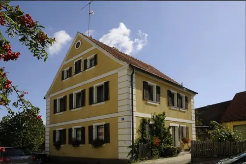Gelbes fränkisches Wohnhaus des Hofs Gößwein im Sommer mit Vogelbeerbaum